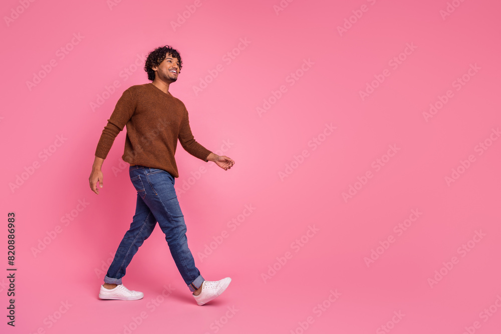 Photo of funny positive glad man wear stylish brown clothes walk empty space isolated on pink color background