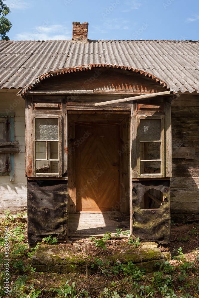 Abandoned old wooden house among the green trees and tall grass. Rural landscape. Ukraine. Abandoned old wooden house among the green trees and tall grass. Rural landscape. Ukraine.