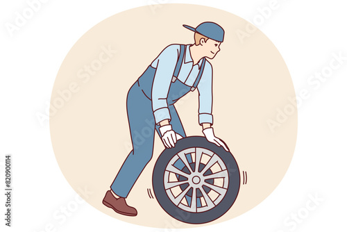 Man automobile repairman changes car wheel to new one to avoid accident or perform scheduled inspection. Employee of garage car workshop conducts vehicle maintenance or pre-sale preparation