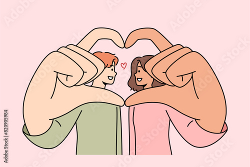 Romantic couple shows symbol of love and devotion, giving heart from hands and wanting to kiss. Multinational man and woman are proud of mutual love or opportunity to build united family