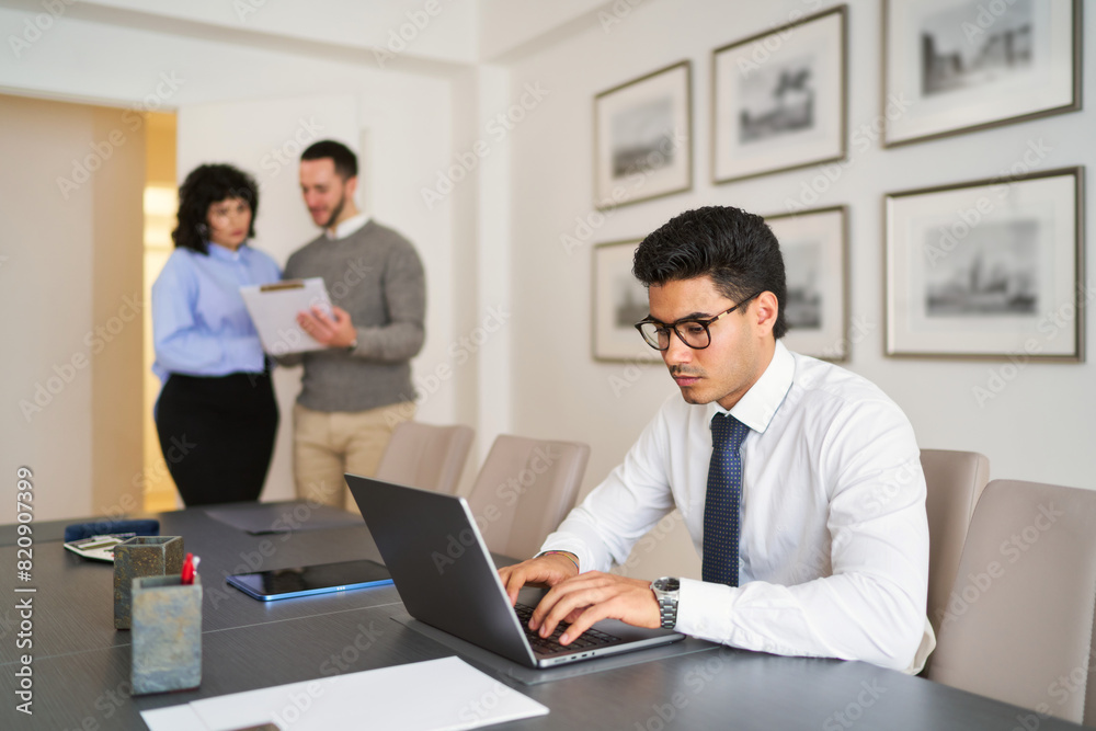 A man is typing on a laptop in front of a group of people A man is typing on a laptop in front of a group of people