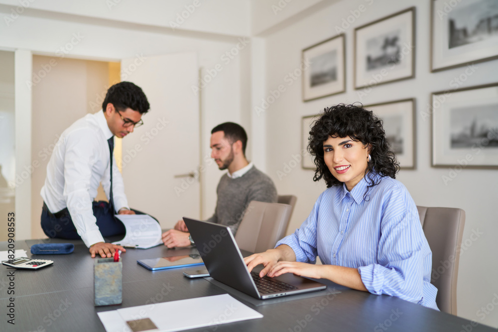 A woman is sitting at a desk with a laptop and a man is standing behind her A woman is sitting at a desk with a laptop and a man is standing behind her