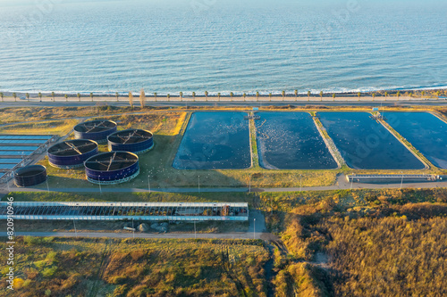 neAerial view of modern sewage treatment plant by the sea. Industrial water treatment with round water tanks for sewage recycling from drone view. Waste water management. view. Waste water management