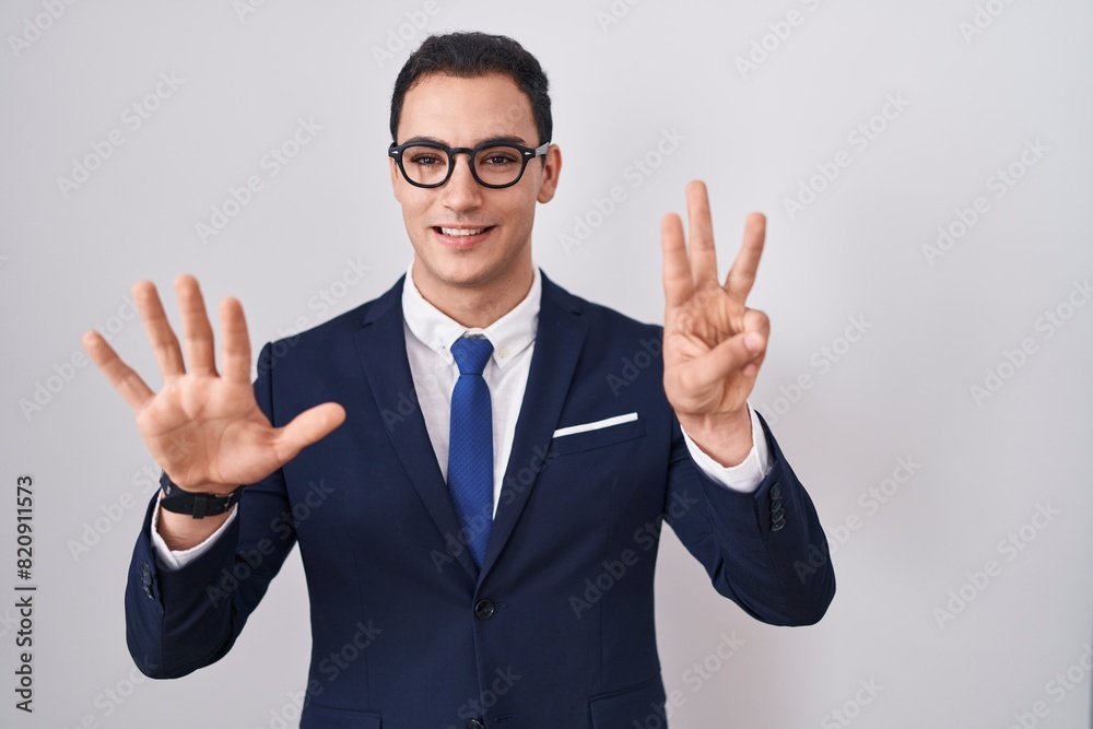 Young hispanic man wearing suit and tie showing and pointing up with fingers number eight while smiling confident and happy. Young hispanic man wearing suit and tie showing and pointing up with fingers number eight while smiling confident and happy.