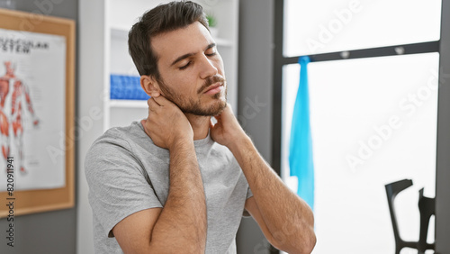 Photography Hispanic man with beard feeling neck pain in a well-lit physiotherapy clinic's r