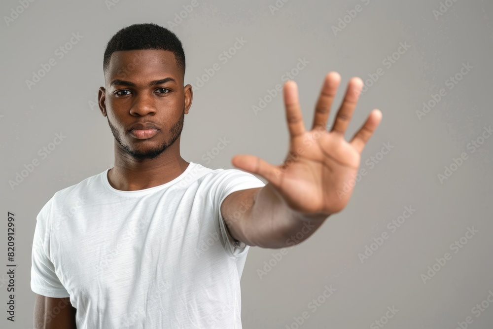 Handsome African American man showing a stop gesture with his palm outstretched to make a no or end gesture. Handsome African American man showing a stop gesture with his palm outstretched to make a no or end gesture.