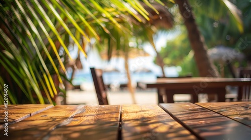 Fototapeta Naklejka Na Ścianę i Meble -  Empty wooden table top for product display, presentation stage. Tropical summer, palm trees, beach bar, white sand and blue ocean in the background.	