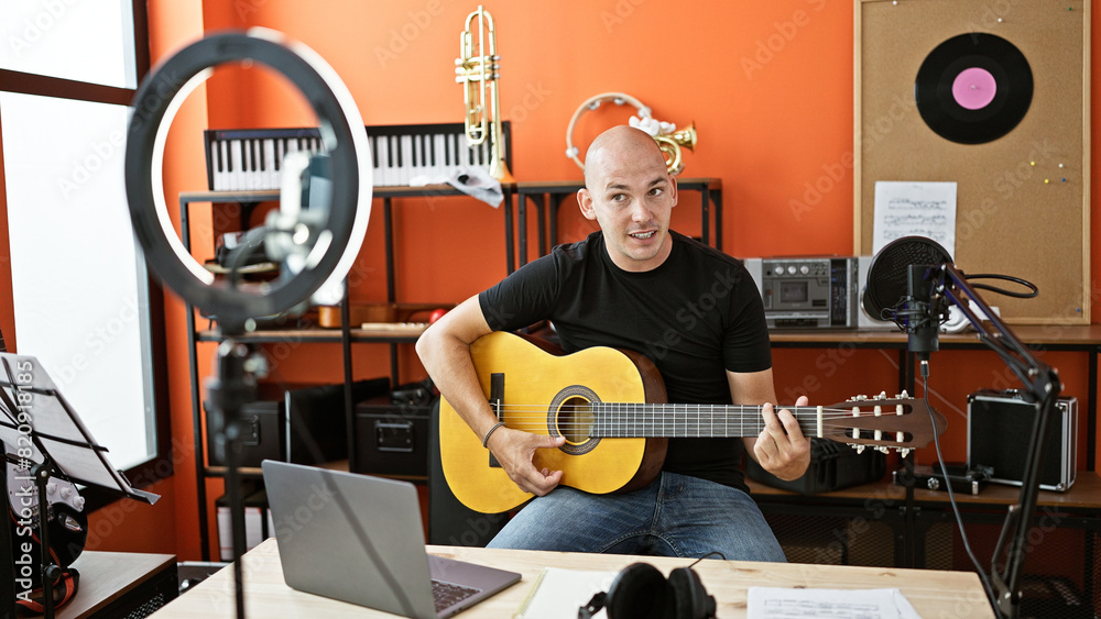 Fototapeta premium Young hispanic man musician having online classical guitar lesson at music studio