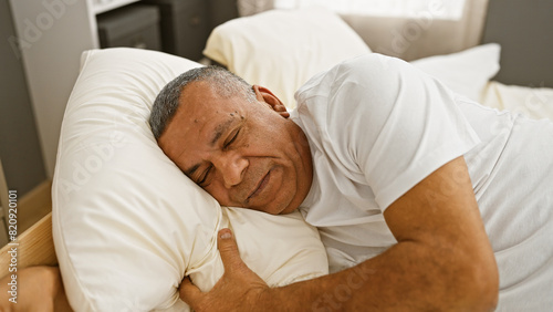 Mature hispanic man sleeping peacefully in a cozy bedroom setting, embodying relaxation and comfort.