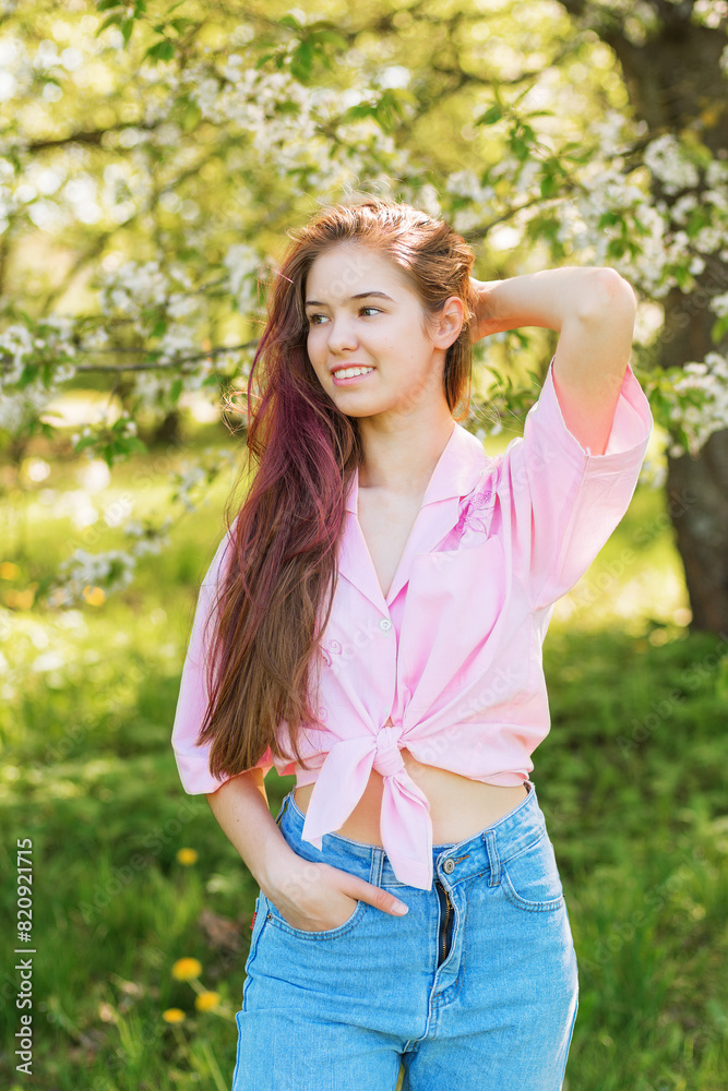 Spring.Beautiful romantic modern girl in a pink shirt and jeans standing in a blooming garden. Young model between apple trees. Spring.Beautiful romantic modern girl in a pink shirt and jeans standing in a blooming garden. Young model between apple trees.