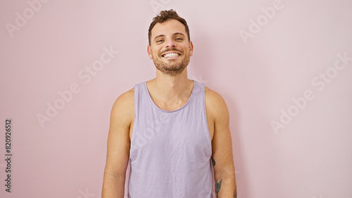 Smiling young hispanic man with beard in casual sleeveless shirt against a plain pink background © Krakenimages.com
