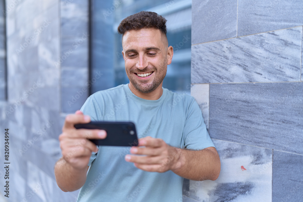 Young hispanic man smiling confident watching video on smartphone at street Young hispanic man smiling confident watching video on smartphone at street