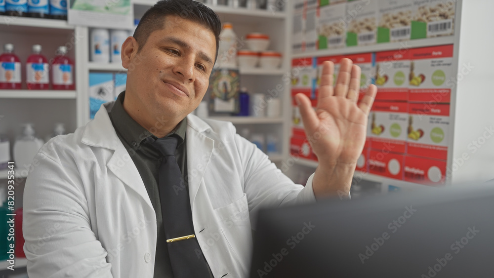 Hispanic pharmacist waving in a drugstore with shelves stocked with products in the background. Hispanic pharmacist waving in a drugstore with shelves stocked with products in the background.