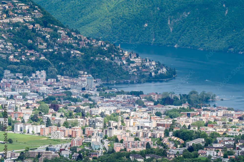 Fototapeta premium view of the town of Lugano in Italy. charming town, lush green hills, serene waters, lake lugano, colorful buildings, traditional italian architecture, waterfront, vibrant town square, bustling 