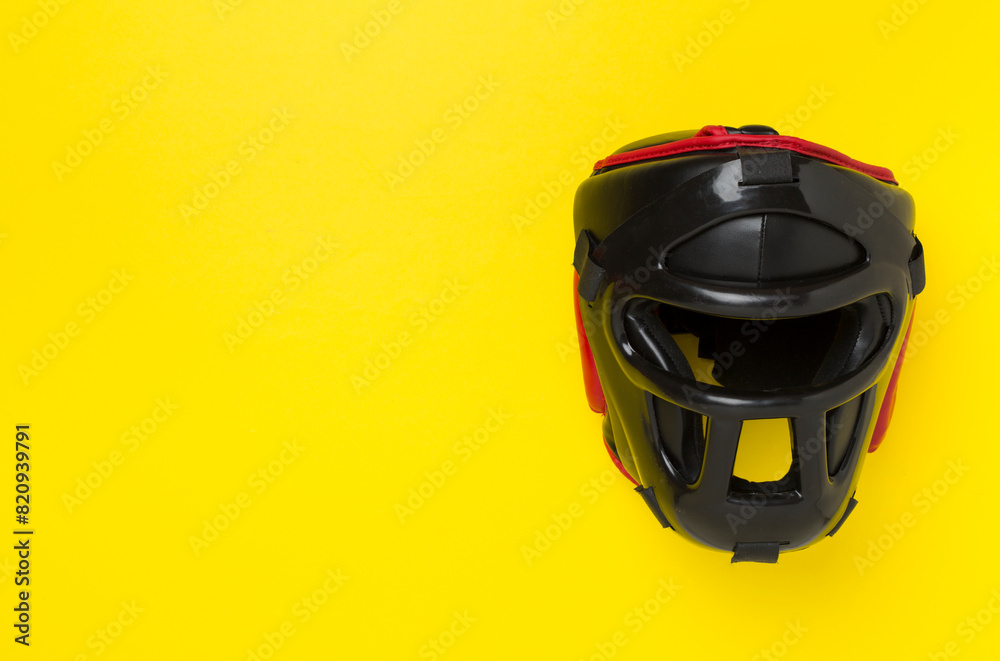 Fototapeta premium Black leather boxing helmet on color background, top view.