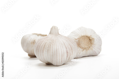 Three Whole Garlic Bulbs With Cloves on a White Background in Bright Daylight