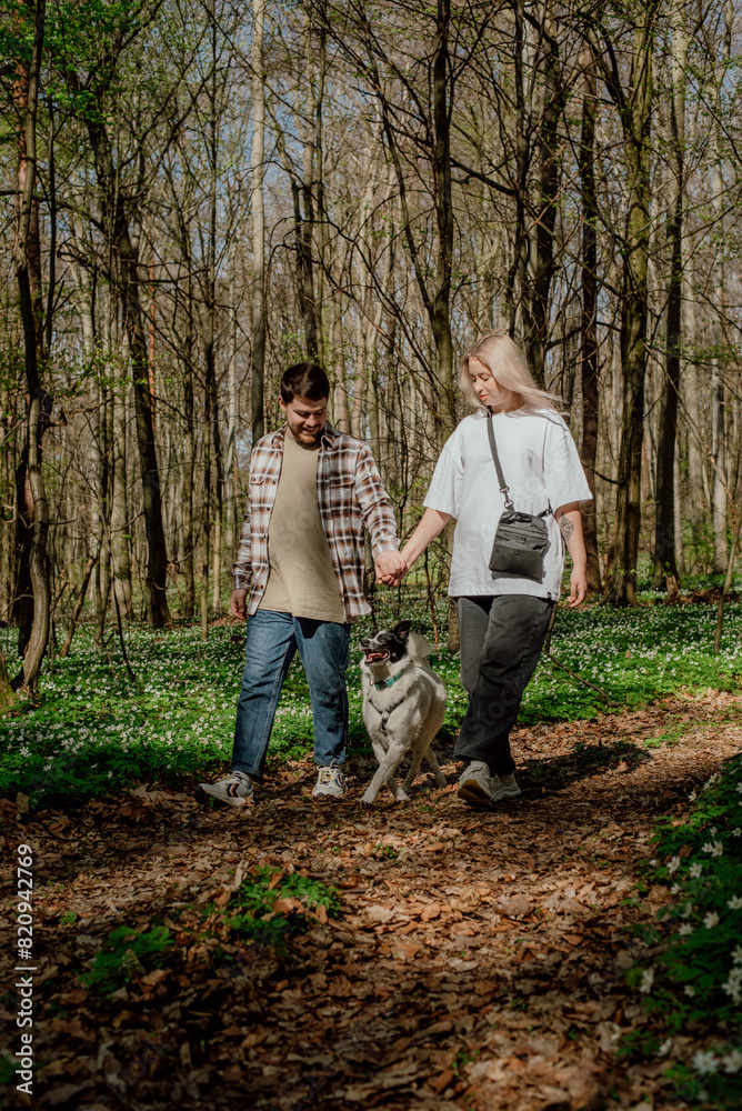 young cheerful couple playing with their cute mixed breed rescue dog outdoors in the forest