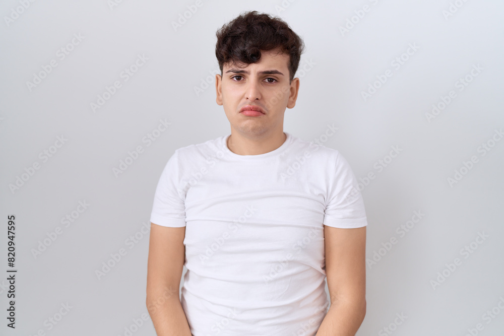Young non binary man wearing casual white t shirt depressed and worry for distress, crying angry and afraid. sad expression. Young non binary man wearing casual white t shirt depressed and worry for distress, crying angry and afraid. sad expression.