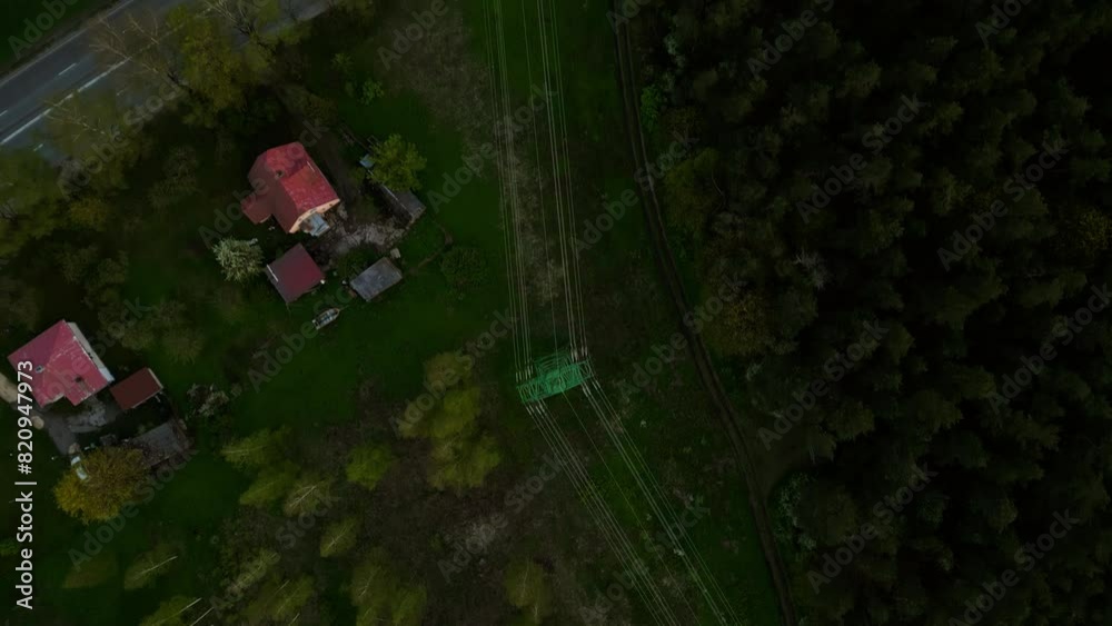 Aerial view of homes in the countryside surrounded by lush forest, with railway tracks weaving through the landscape Aerial view of homes in the countryside surrounded by lush forest, with railway tracks weaving through the landscape