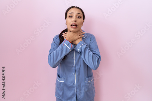 Young arab woman wearing blue pajama shouting suffocate because painful strangle. health problem. asphyxiate and suicide concept.