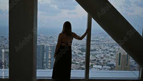 A woman gazes at the dubai skyline from an observatory, capturing the cityscape and tranquility within the urban landscape. © Krakenimages.com