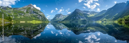 Calm lake reflects towering mountains under blue skies.