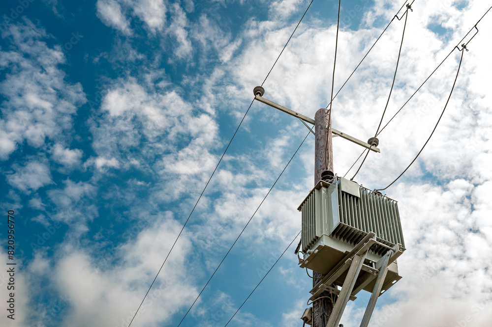 Newly installed, next generation electrical transformer mounted on a wooden pole. The power lines in view are used to power a large village in the east of England. Newly installed, next generation electrical transformer mounted on a wooden pole. The power lines in view are used to power a large village in the east of England.