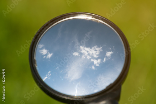Blue sky and white clouds, reflected in a bicycle mirror.