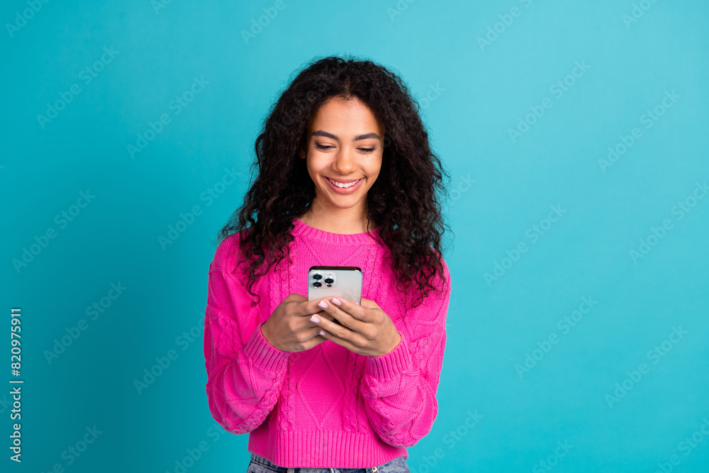 Photo of lovely young girl use smart phone wear pink pullover isolated on teal color background Photo of lovely young girl use smart phone wear pink pullover isolated on teal color background