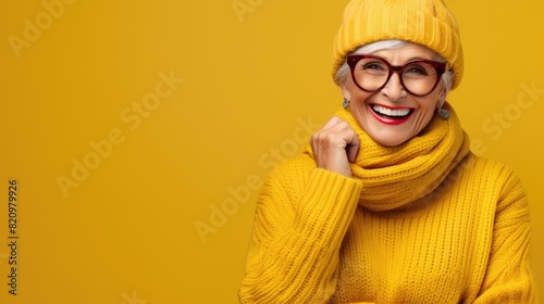 Joyful Senior Woman in Yellow Outfit with Chic Glasses on Vibrant Background © Anastasiia