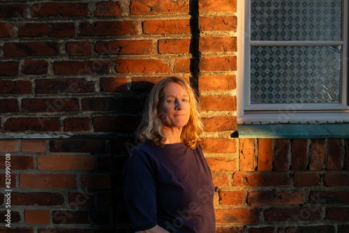 Canvas Print Stockholm, Sweden A woman portrait at the brick orange facade of the Hogalid Church at sunset