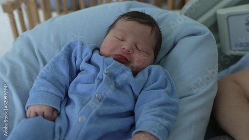 Newborn baby sleeping peacefully in a cozy outfit, resting on a cushion, representing tranquility and innocence, healthcare setting, postnatal care, early life, family love, and nurturing photo