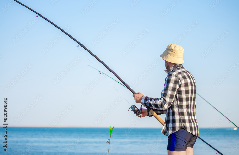 Fishing. A man catches fish with a spinning rod. The guy swings his fishing rod and throws the bait, waiting for a bite by pulling up the reel. Fishing. A man catches fish with a spinning rod. The guy swings his fishing rod and throws the bait, waiting for a bite by pulling up the reel.