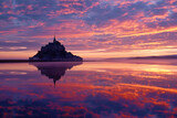 Mont Saint-Michel silhouetted against a vibrant sunrise over the bay