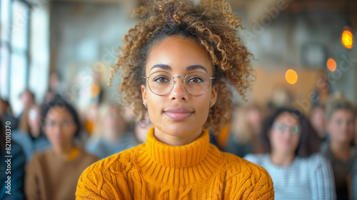 Woman wearing glasses stands confidently in front of a group of people photo