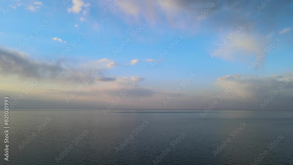 Aerial view from a drone flying above a very large lake with pastel-colored clouds in a bright blue sky. The sky colors are reflecting in the water.
Aerial view from a drone flying above a very large lake with pastel-colored clouds in a bright blue sky. The sky colors are reflecting in the water.