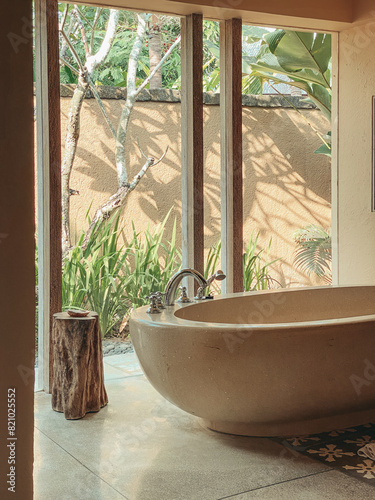 A beautiful stone bathtub in a bathroom with glass window