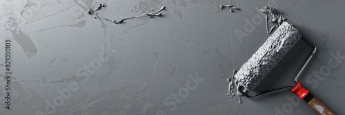 A roller brush applying grey paint along a textured wall imparting a fresh coat, in a wide panoramic shot photo