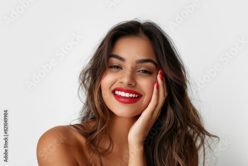 Happy Indian woman with dark hair and red nails, posing with a radiant smile and a hand on her cheek