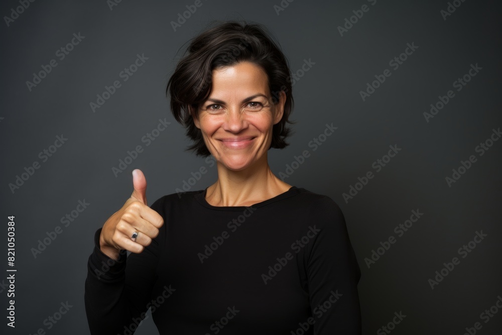 Portrait of a glad woman in her 40s showing a thumb up on minimalist or empty room background Portrait of a glad woman in her 40s showing a thumb up on minimalist or empty room background