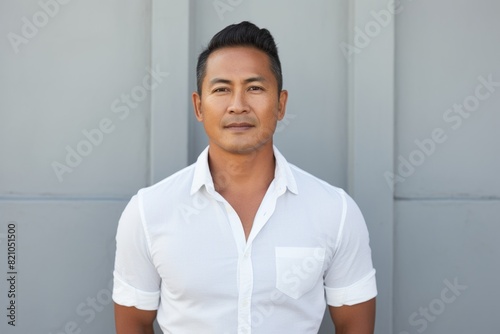 Portrait of a happy asian man in his 40s smiling at the camera in front of minimalist or empty room background