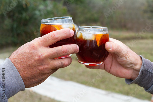 Dos hombres brindando con un cocktail al aire libre. Vista de frente y de cerca. Copy space