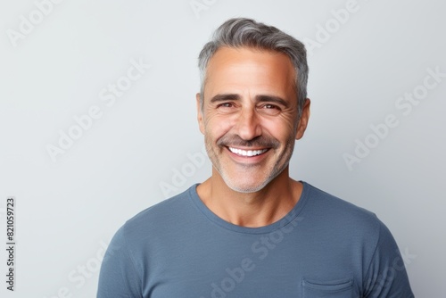 Portrait of a cheerful man in his 50s smiling at the camera in minimalist or empty room background