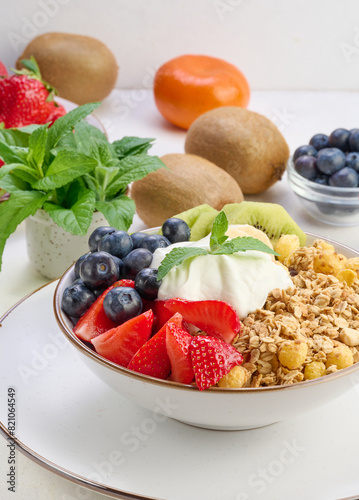 Granola with strawberries  kiwi  banana and blueberries in a round plate