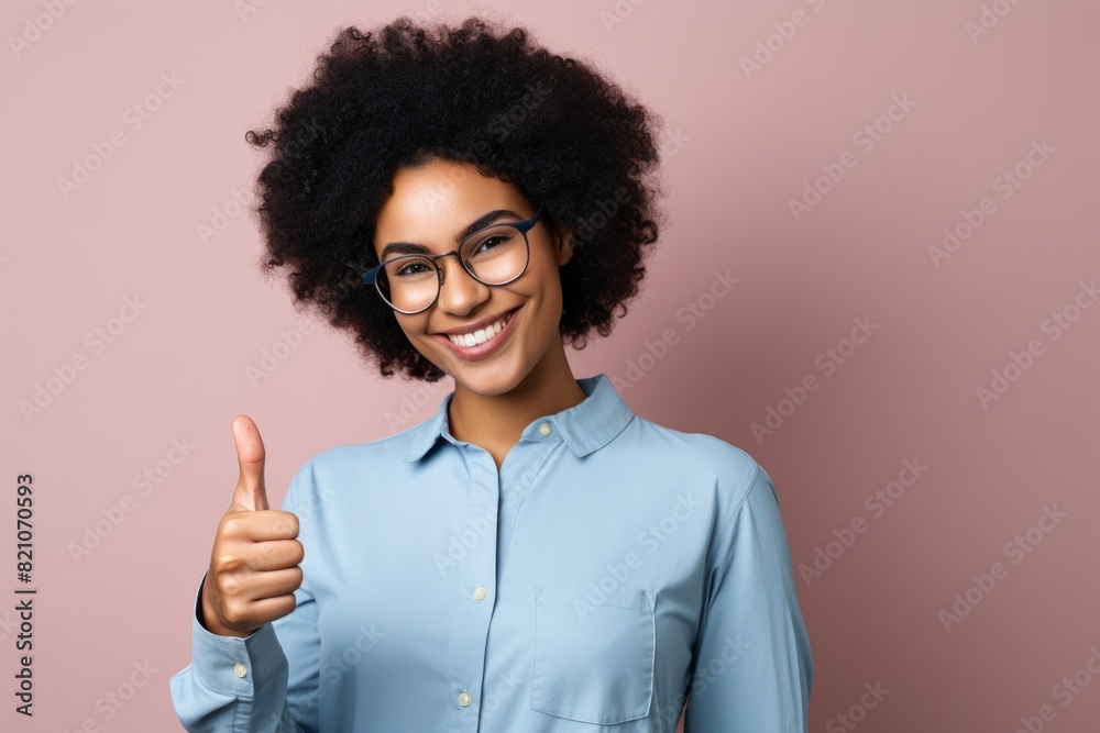 Portrait of a smiling afro-american woman in her 20s showing a thumb up while standing against minimalist or empty room background Portrait of a smiling afro-american woman in her 20s showing a thumb up while standing against minimalist or empty room background