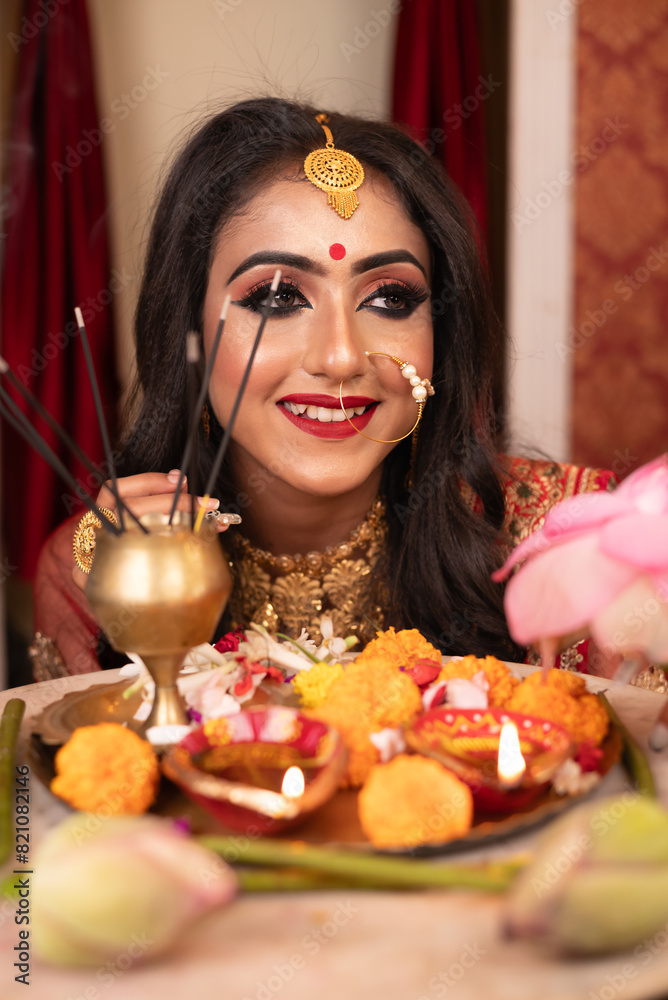 Φωτογραφία Portrait of pretty young Indian woman dressed in a traditional lehenga, gold jewellery and bangles, smiles tender in studio lighting indoor
