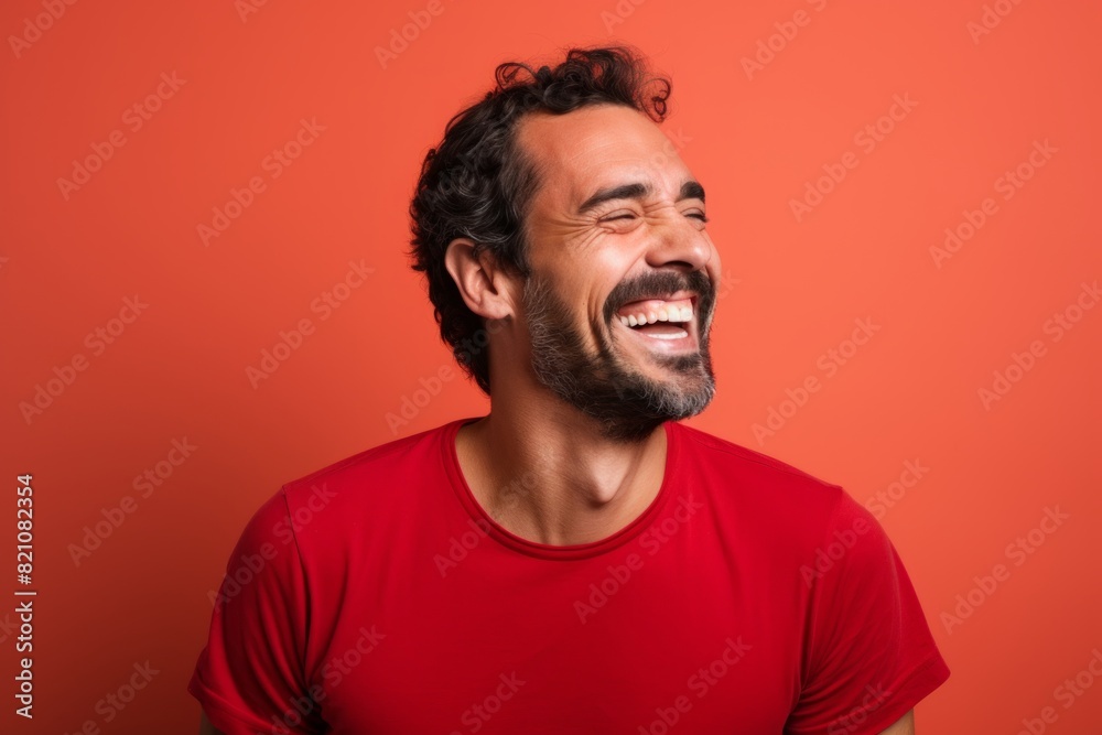 Portrait of a smiling man in his 30s laughing while standing against solid color backdrop Portrait of a smiling man in his 30s laughing while standing against solid color backdrop