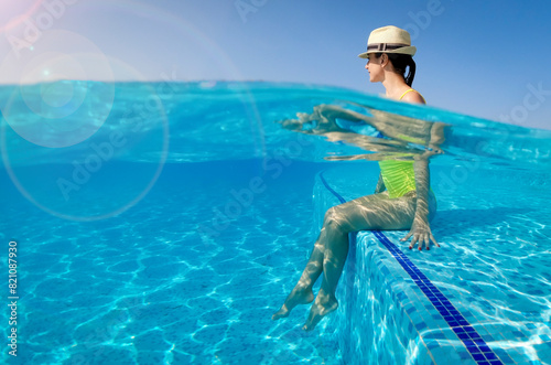 Girl in a hat sitting in the pool enjoys cool on a sunny day. Underwater split