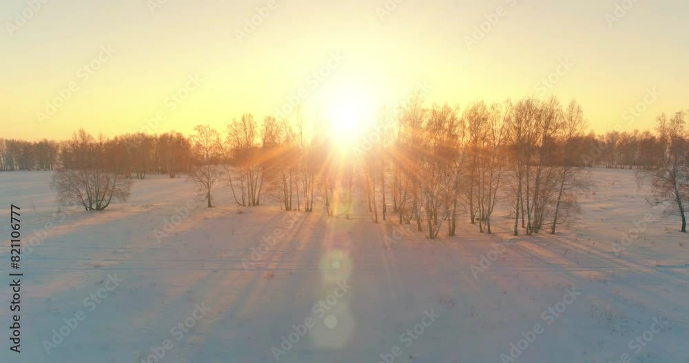 Aerial drone view of cold winter landscape with arctic field, trees covered with frost snow and morning sun rays over horizon. Extreme weather. Aerial drone view of cold winter landscape with arctic field, trees covered with frost snow and morning sun rays over horizon. Extreme weather.