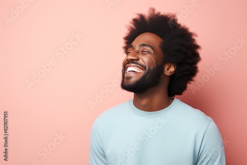 Portrait of a satisfied afro-american man in his 30s laughing in solid pastel color wall